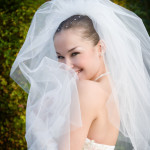 a smiling beautiful bride hides into her veil